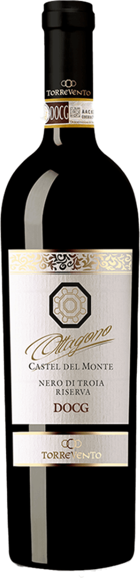 Het label heeft een klassiek ontwerp met een wit achtergrond en gouden decoratieve elementen. Bovenaan staat 'Ottagono' in sierlijke letters, met daaronder de naam van de wijn 'Castel del Monte Nero di Troia Riserva DOCG'. Er is een geometrisch embleem dat lijkt op een achtkantig symbool, centraal geplaatst.